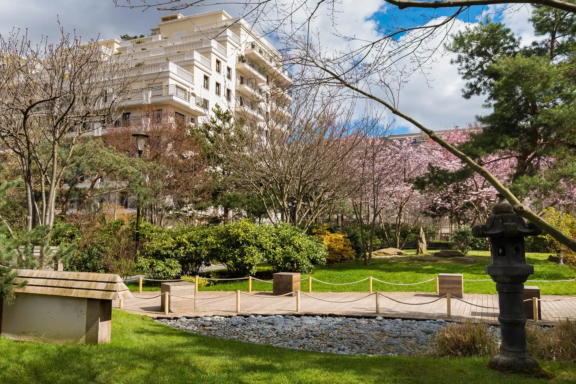 Jardin japonais avec cerisiers en fleurs et lanterne en pierre devant un immeuble, quartier Collange à Levallois-Perret