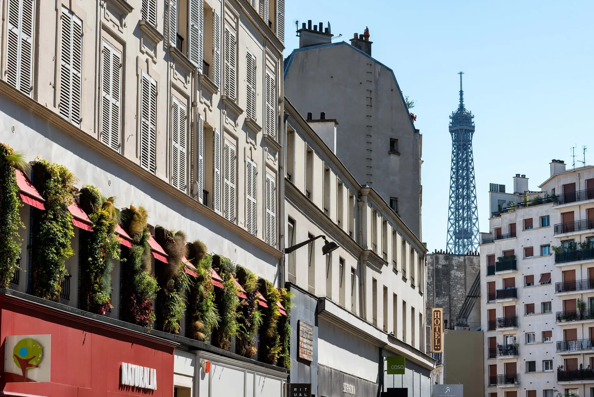 Rue commerçante aux façades fleuries avec la tour Eiffel en perspective, quartier Village Passy, Paris 16e