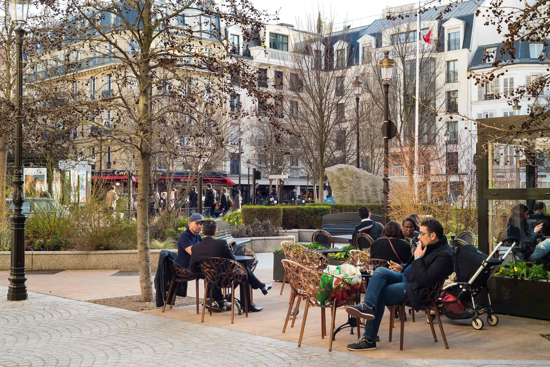 Terrasses de café sur une place arborée animée, quartier Mairie à Levallois-Perret