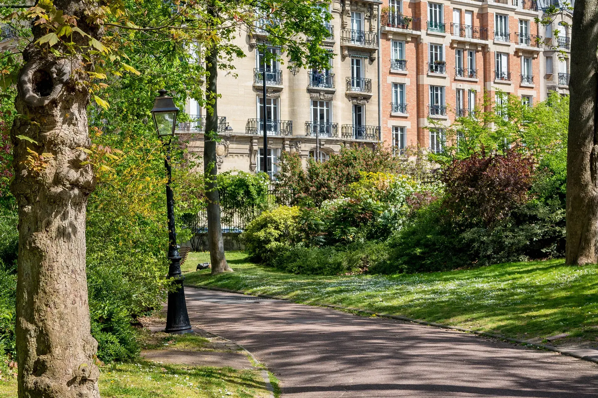 Parc verdoyant et lampadaire devant des immeubles haussmanniens, quartier Les Couronnes à Courbevoie