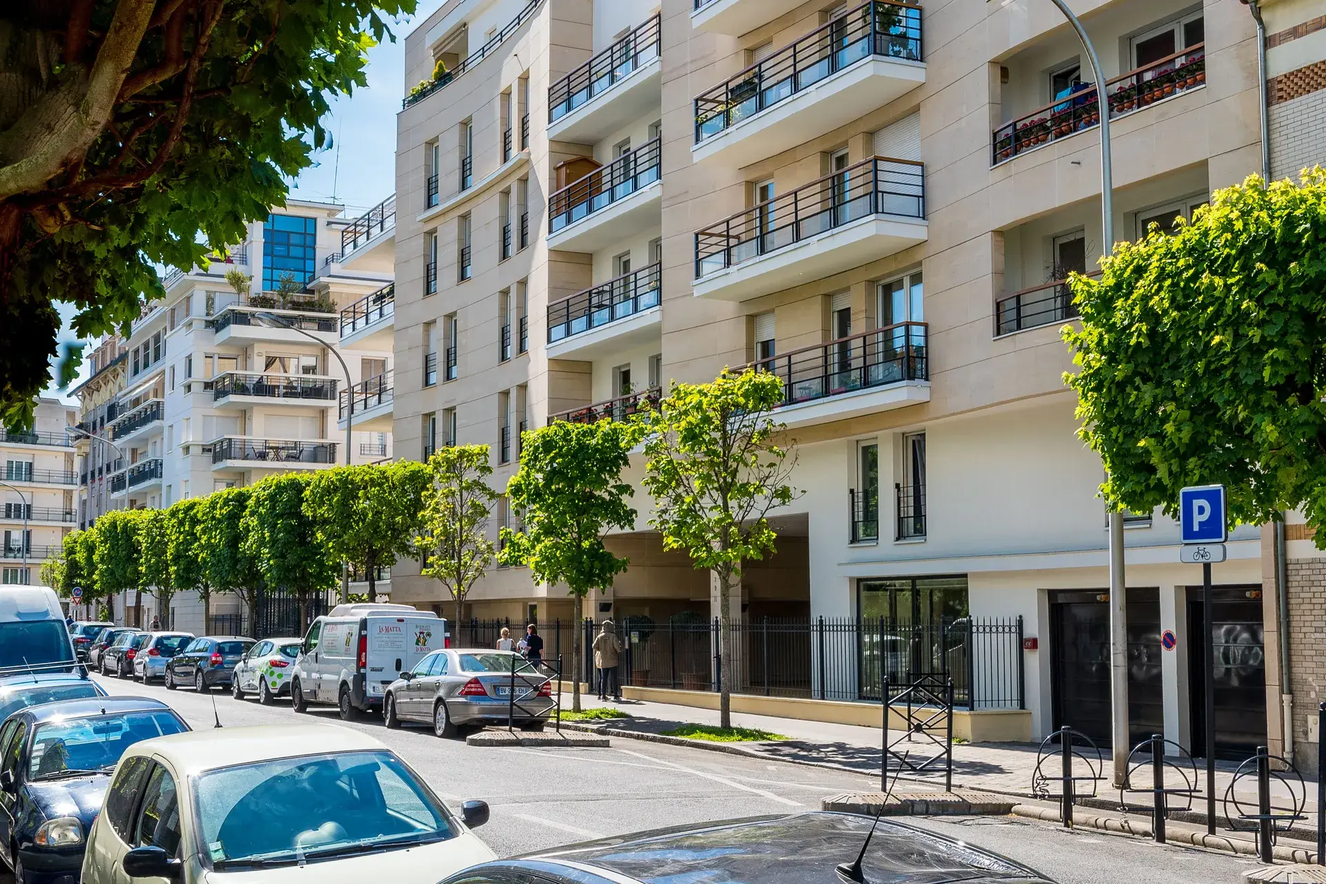 Rue résidentielle bordée d'immeubles récents et d'arbres taillés, quartier Marceau à Courbevoie