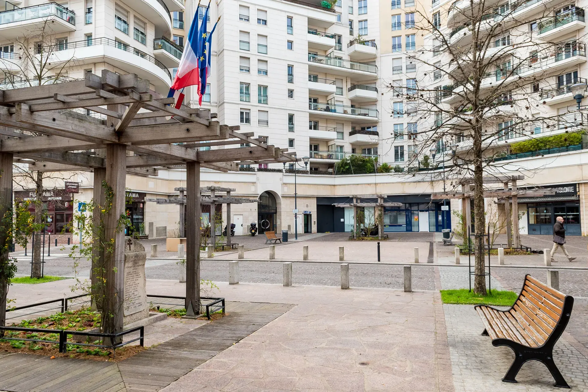Place arborée sous pergola, drapeau français et résidences, quartier Marceau à Courbevoie