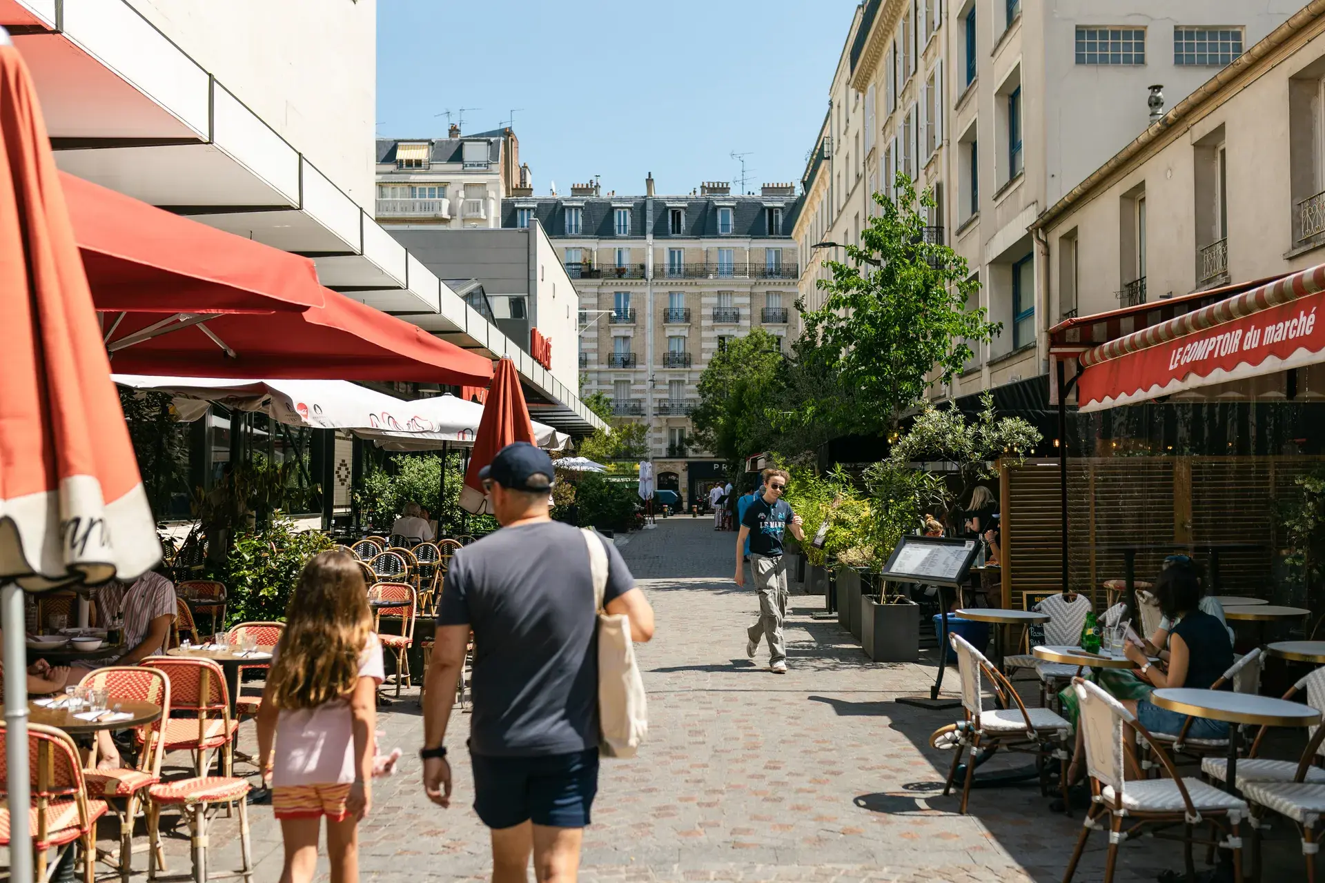 Rue piétonne pavée animée bordée de terrasses et d'immeubles haussmanniens, quartier Louise Michel à Levallois-Perret