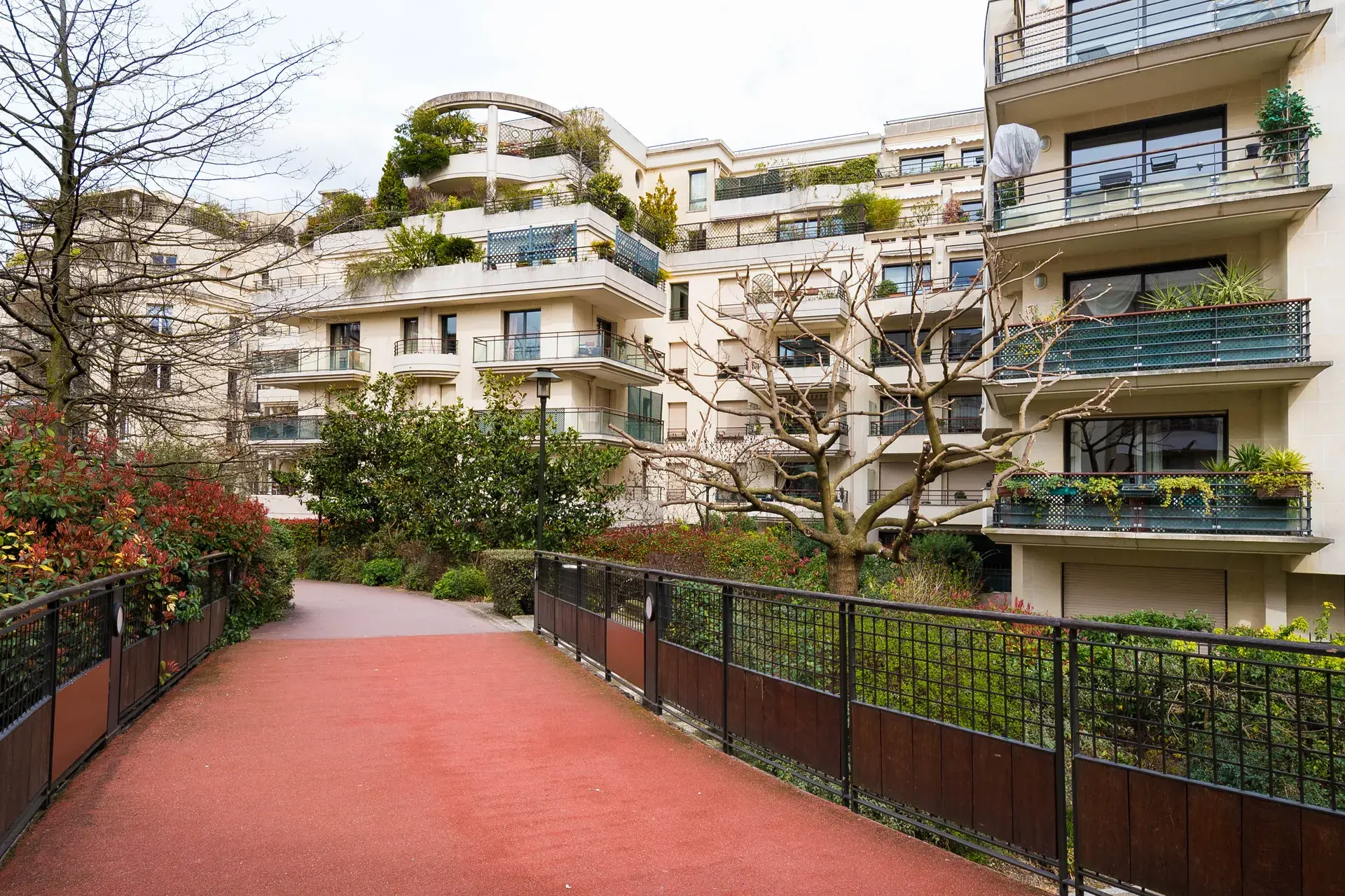 Allée rouge bordée de résidences modernes aux balcons végétalisés, quartier Jean-Zay à Levallois-Perret