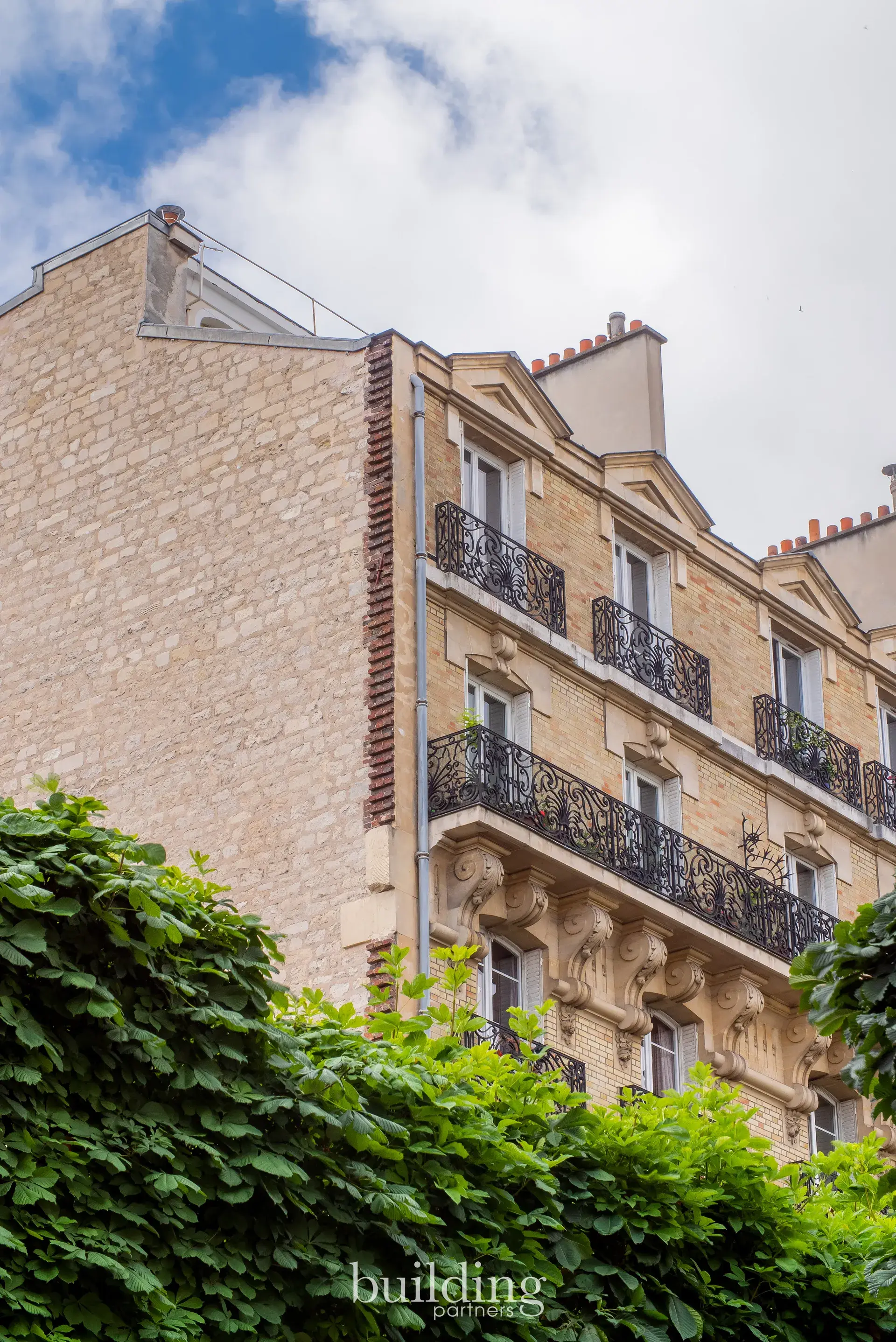 Façade d'un immeuble ancien en pierre aux balcons en fer forgé, quartier Mairie à Levallois-Perret