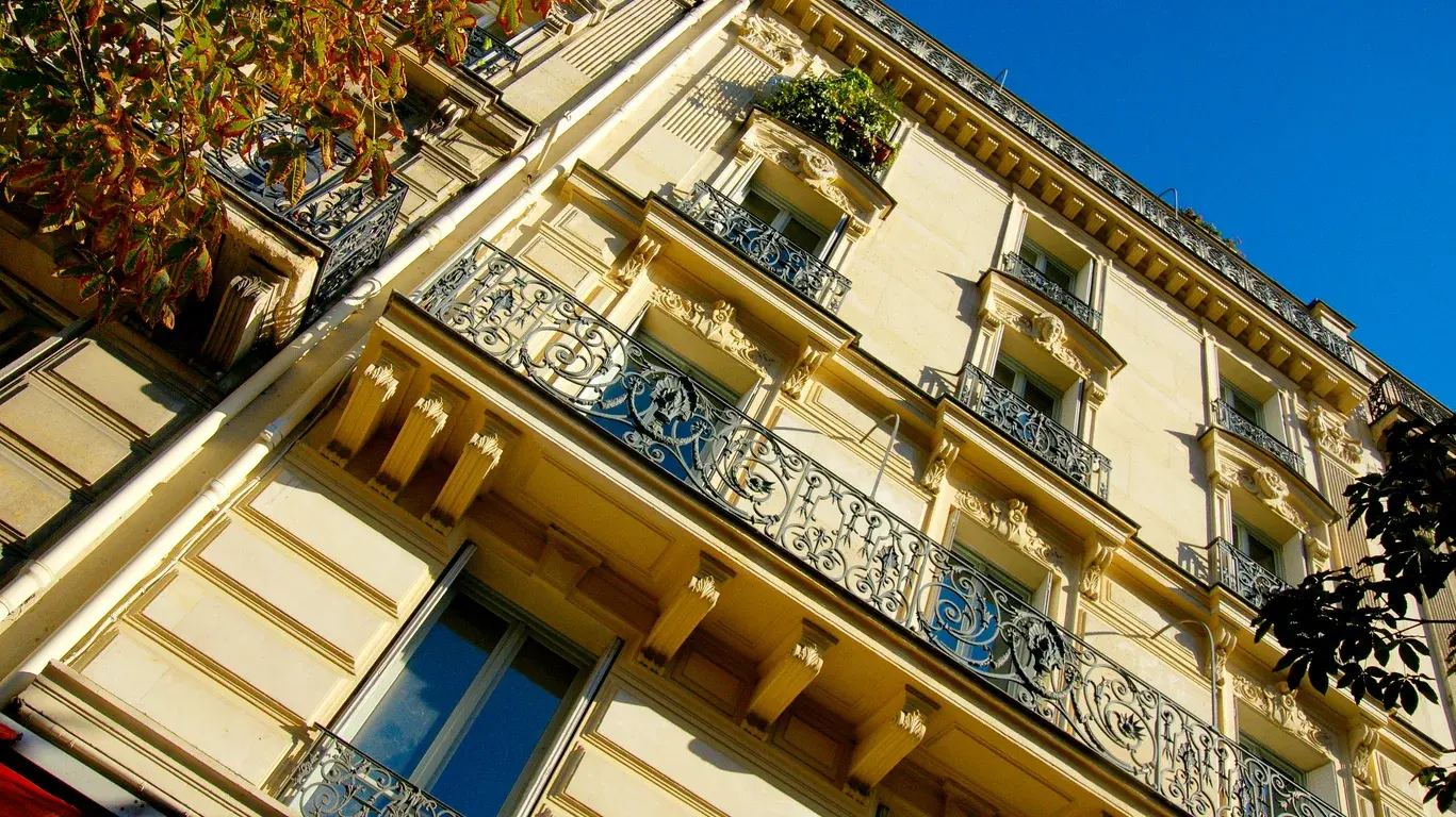 Photo article isolation thermique pour chaleur. Façade classique de l’architecture haussmannienne avec balcons en fer forgé sous un ciel bleu clair et un soleil de plombà Paris, France. Crédits iStock : EL Studio  Référence de la photo : 2277820562.